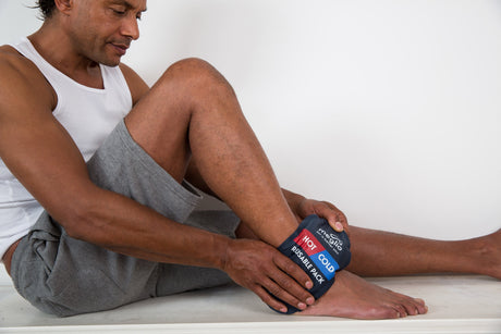 man sat down applying ice pack to ankle after injury
