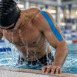 Swimmer at a pool with blue kinesiology tape on his shoulder.